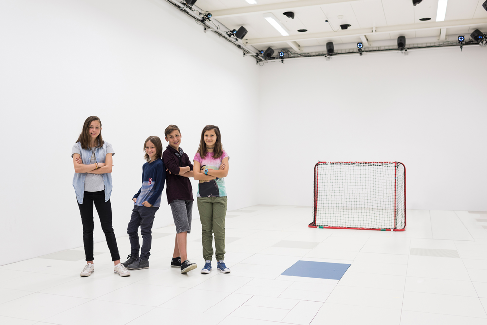 Vier Kinder vor einem Hockeytor in einer Sporthalle